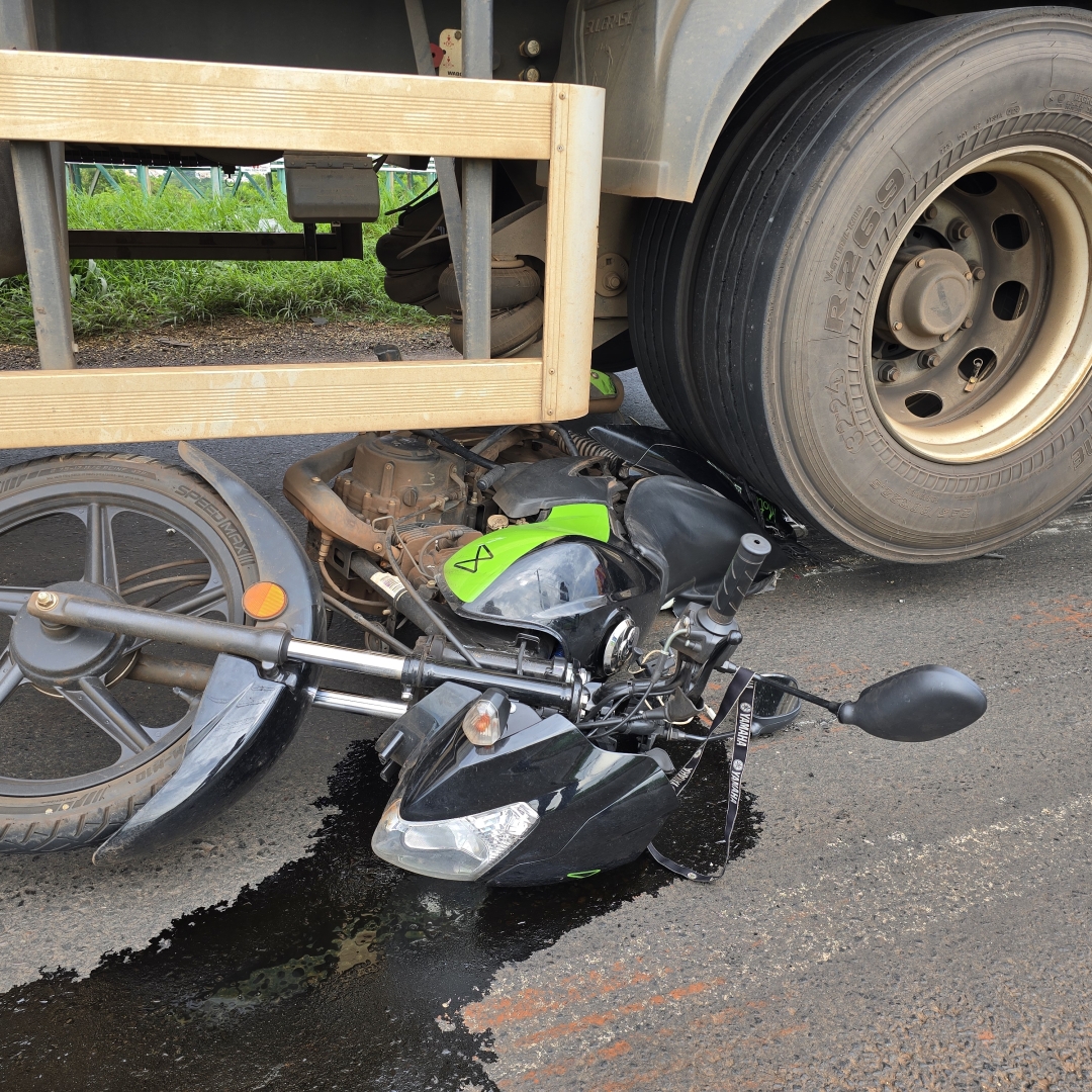 Homem fica debaixo dos rodados de caminhão após moto escorregar em óleo derramado na pista