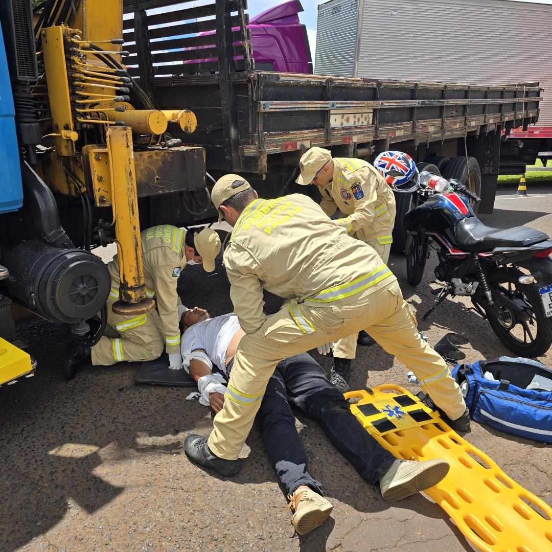 Motociclista escapa da morte após cair debaixo de caminhão 