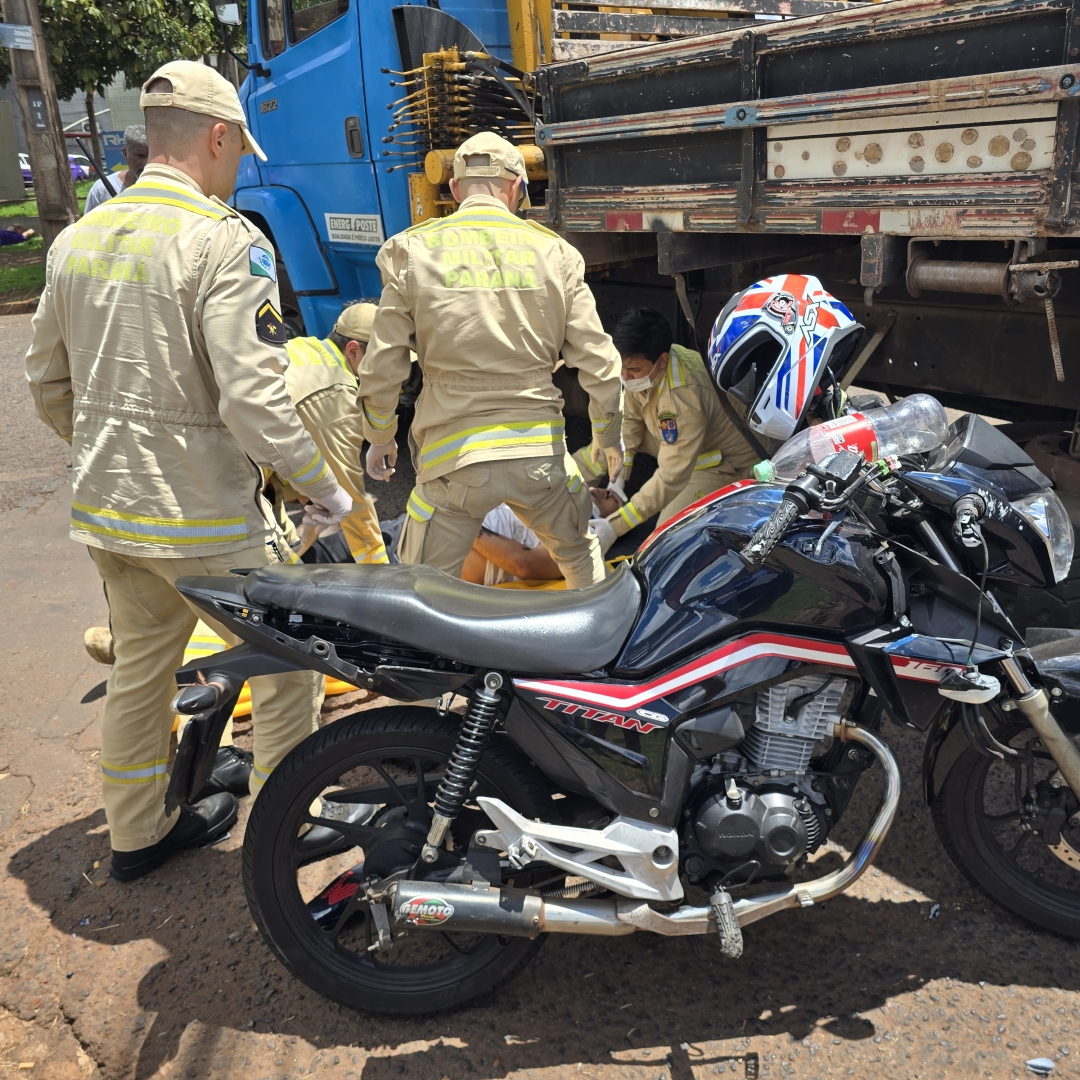 Motociclista escapa da morte após cair debaixo de caminhão 