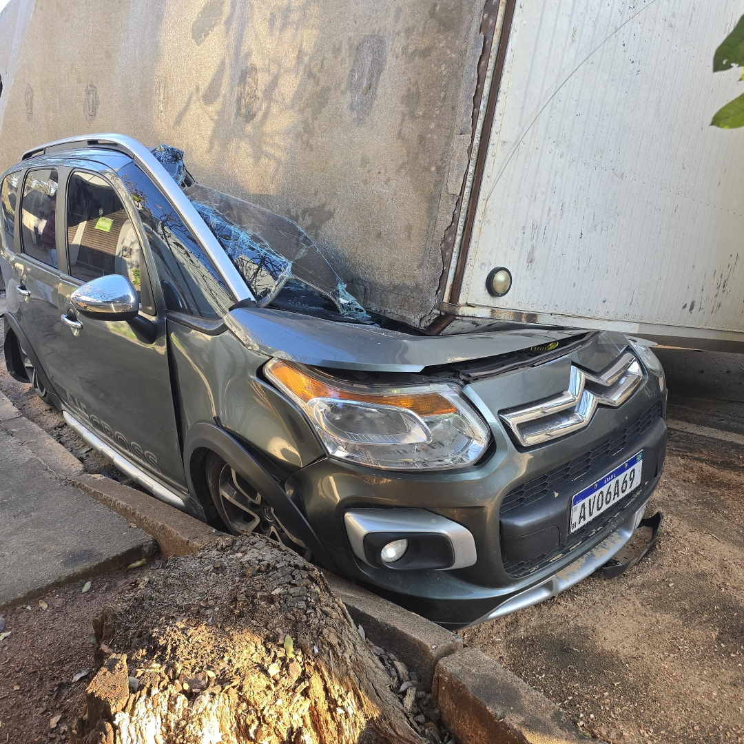 Automóvel fica destruído após carreta tombar e cair sobre automóvel